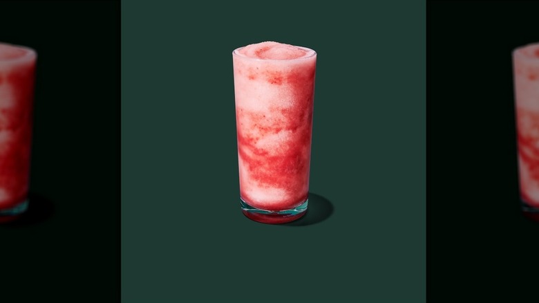 The frozen tropical citrus iced energy with strawberry puree in a clear glass on a green background