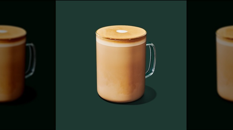 Hot flat white in a glass mug on a green background