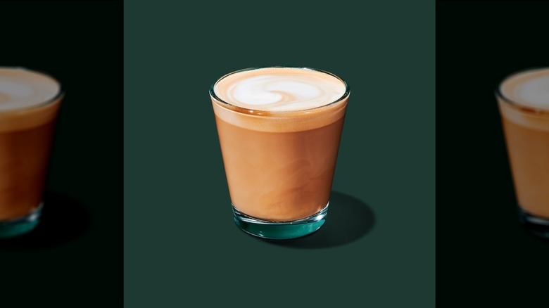 Cortado in a short clear glass on a green background