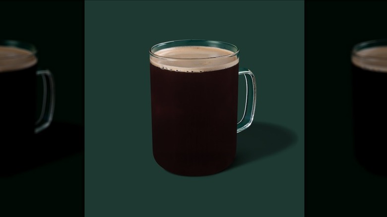Hot Caffè Americano in a glass mug on a green background