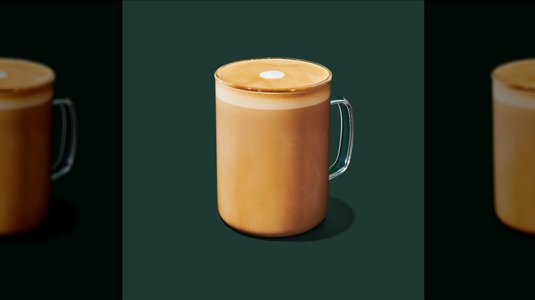 Hot Honey Almondmilk Flat White in a glass mug on a green background
