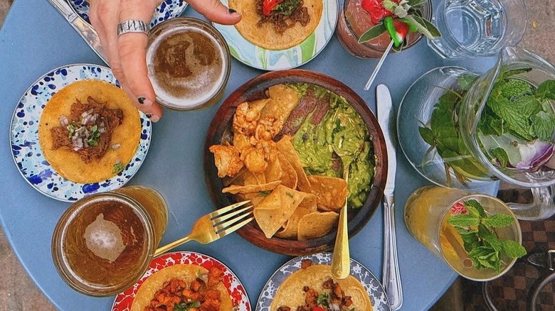A blue table with a selection of tacos and guacamole from Tu Madre