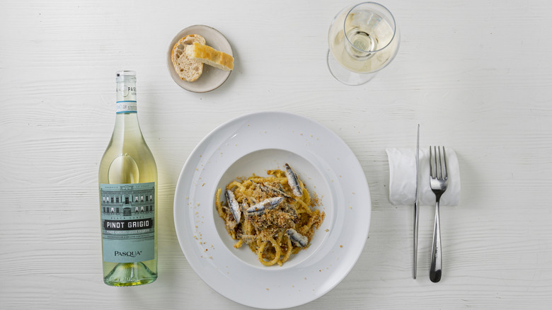 Wine with pasta dish, bread, and utensils