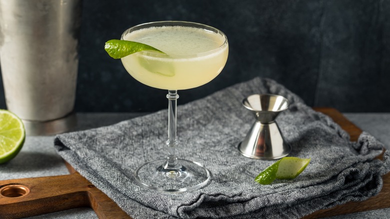 A Gimlet cocktail garnished with a lime peel