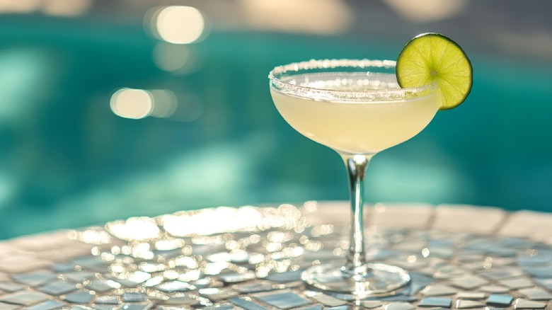 A Margarita cocktail on a table next to a pool