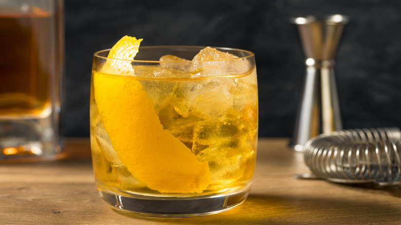 A Rusty Nail cocktail in a glass garnished with lemon peel