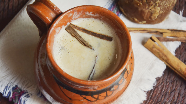 A ceramic mug of atole with cinnamon shards