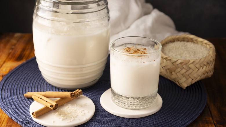 A jug and glass of horchata with cinnamon and rice
