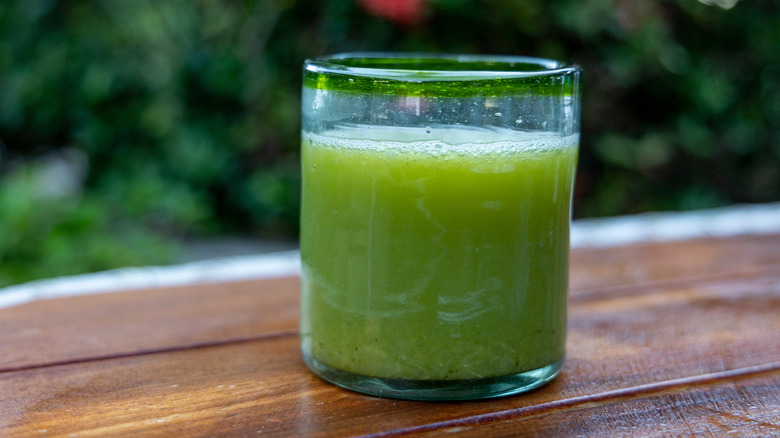 A glass of jugo verde on a wooden table