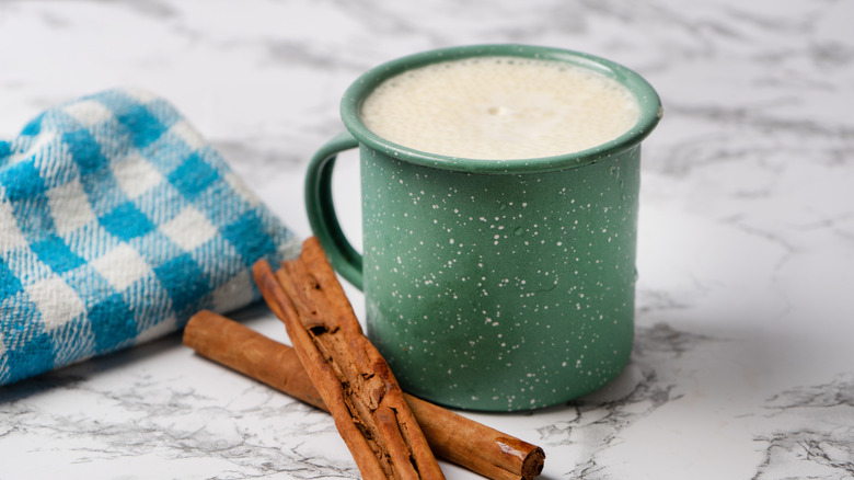 A mug of banana licuado next to cinnamon sticks