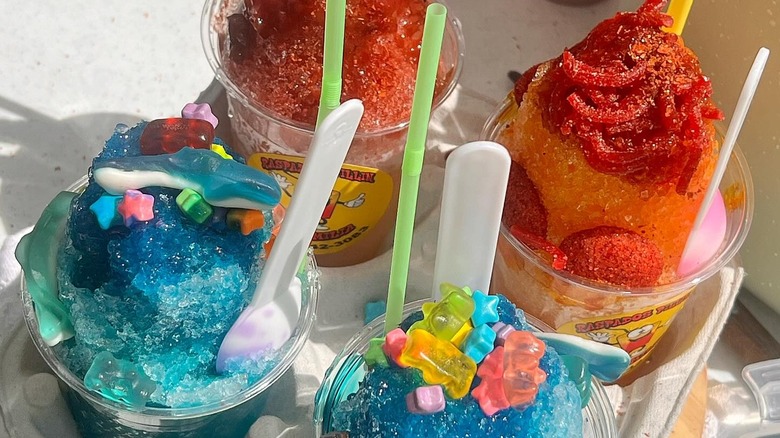 A tray of colorful raspados shaved ice drinks