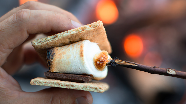 person assembling roasted marshmallow s'more