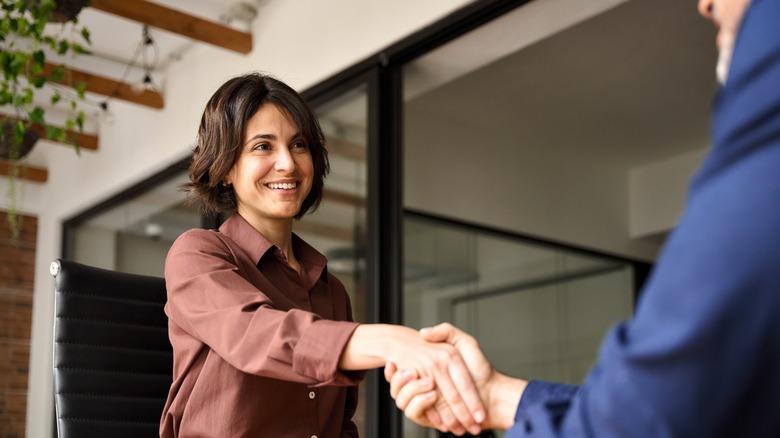 woman in business attire shaking a man's hand