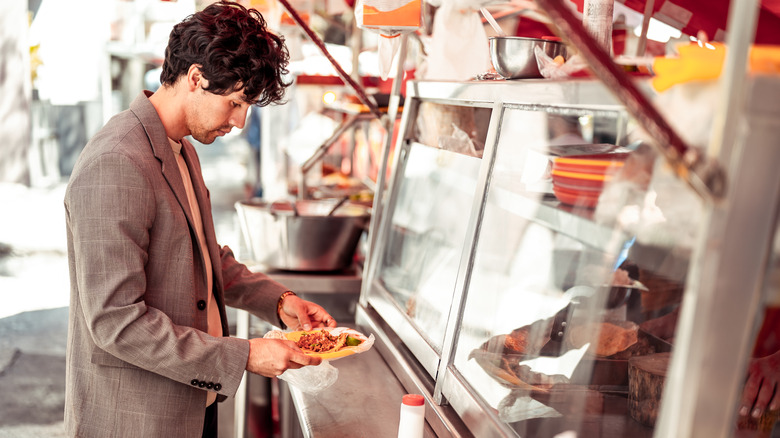 Man with a plate of tacos at a Mexican taco stand