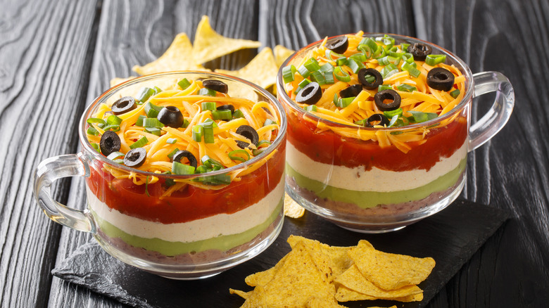 Two glass mugs filled with seven-layer dip