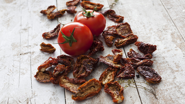 A whole tomato with sun-dried tomatoes on a table