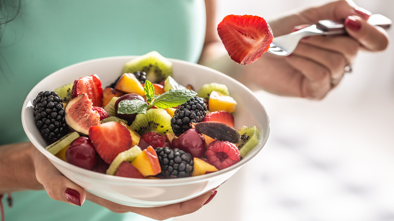 A person holding a bowl of fruit