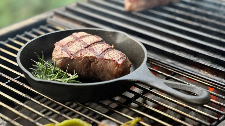 Steak in skillet over grill