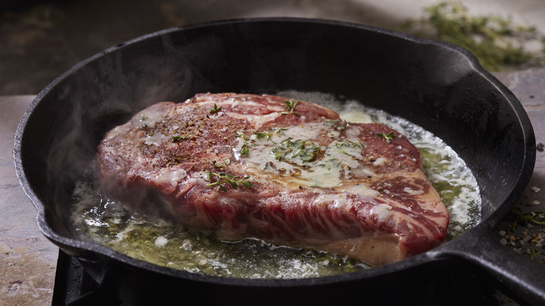 Ribeye cooking in a skillet