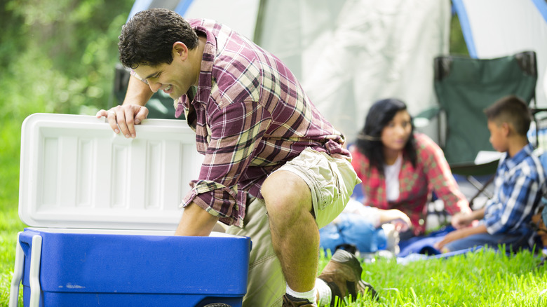 man reaching into cooler