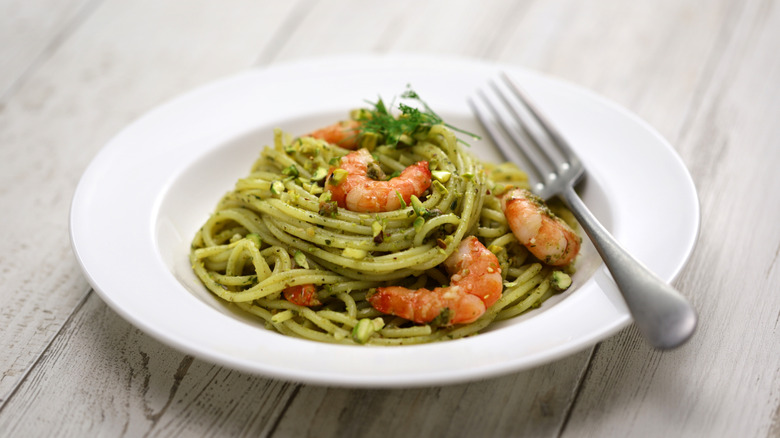 Noodles with pistachio sauce and shrimp in a white bowl
