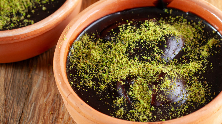 A bowl of chocolate pudding with pistachio powder on top