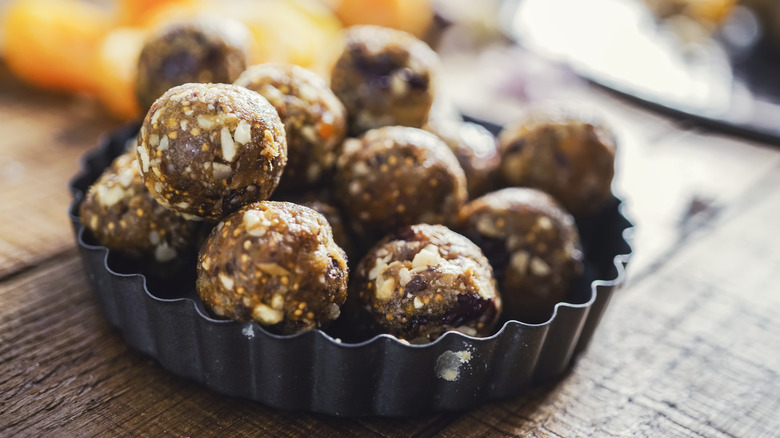 A tin of fruit and nut energy balls on a wooden table