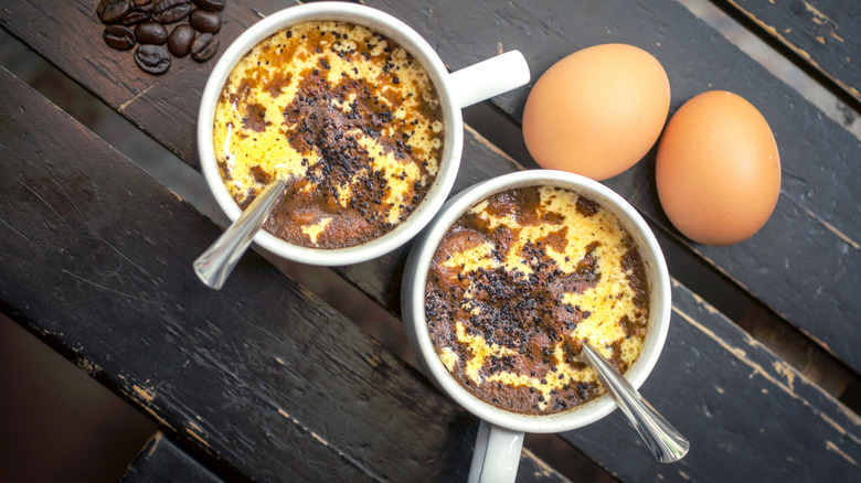 Two cups of cà phê trứng (Vietnamese egg coffee) with eggs on a wooden table