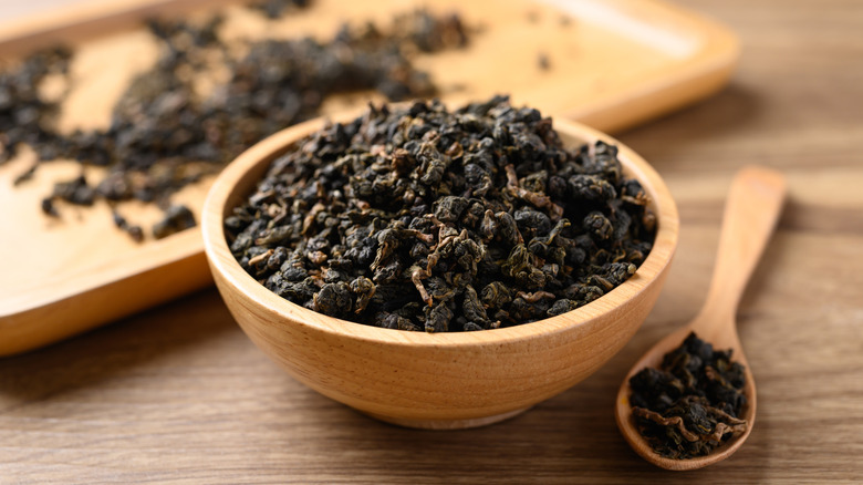Dried loose-leaf tea in a wooden bowl and spoon