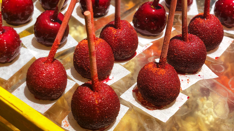 Multiple candy apples covered in chamoy and Tajín