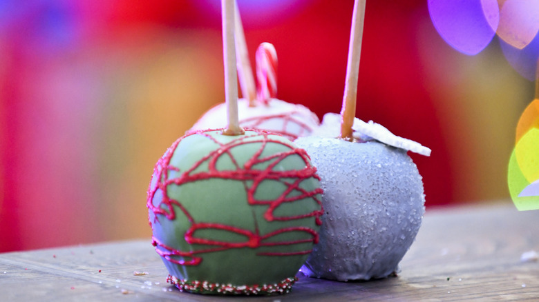 Three colorful candy apples with edible glitter and chocolate drizzle