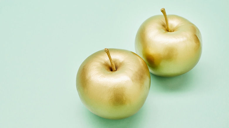 Two apples covered in gold leaf