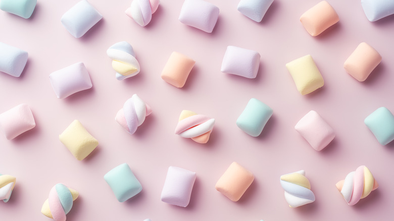 multiple pastel-colored marshmallows on a pink background