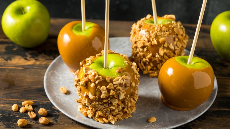 Multiple green apples covered in caramel and peanuts