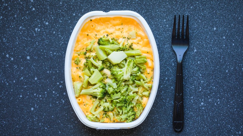 Plastic container of mac and cheese with broccoli and fork