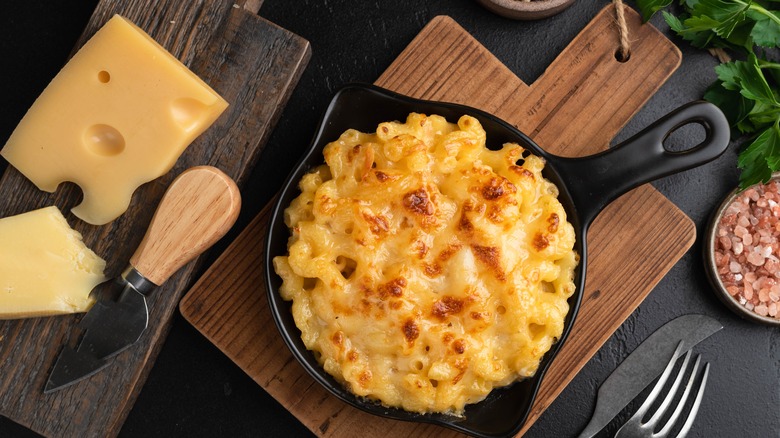 Cheese beside skillet of mac and cheese