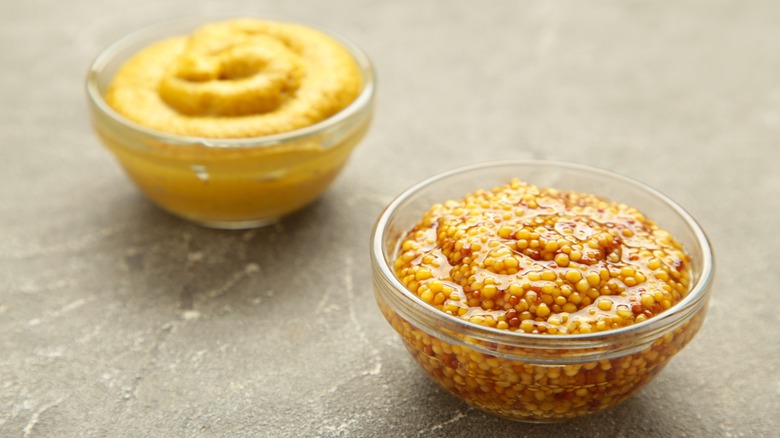 Two small bowls of French mustard and regular mustard