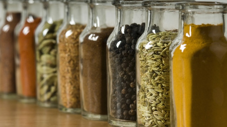 Various spices in glass bottles lined up