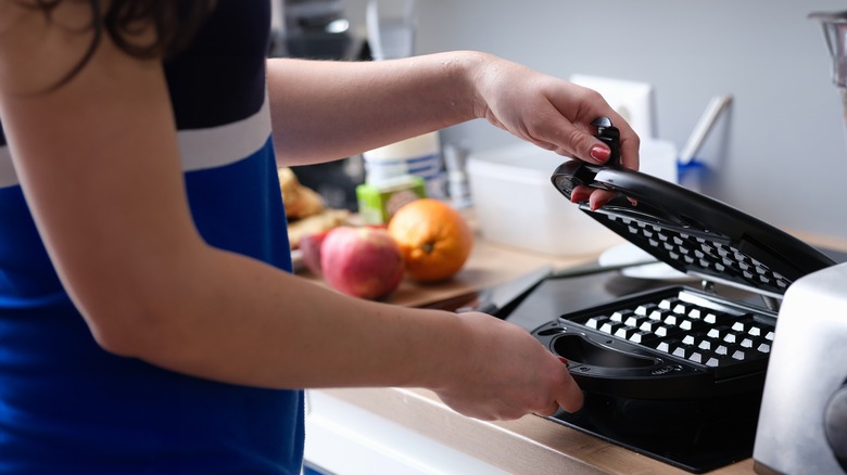 Person using a waffle maker in kitchen