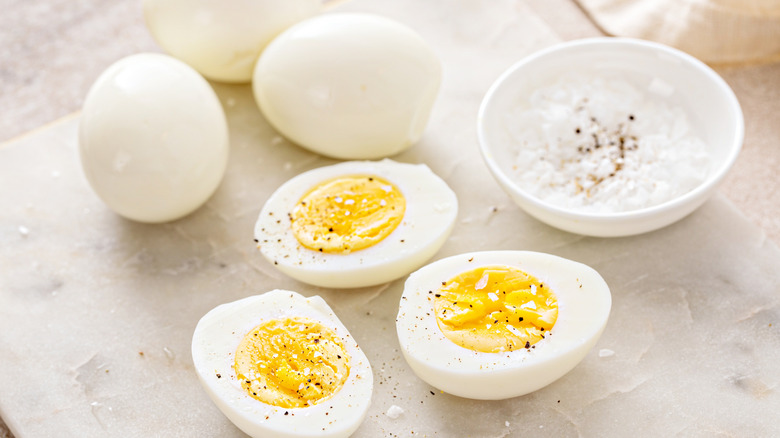 Boiled eggs cut in half next to salt dish