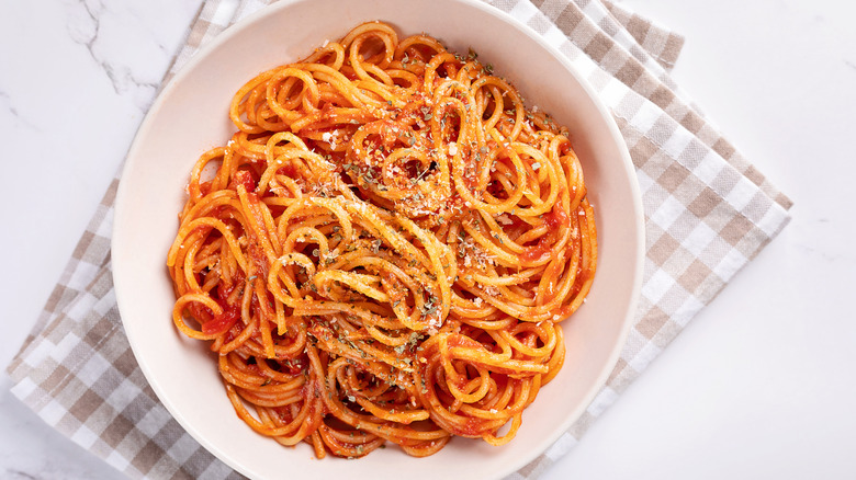 A white bowl of spaghetti with red sauce