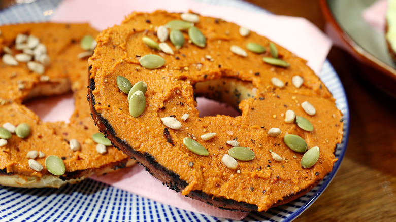 Bagel with hummus and seeds on plate