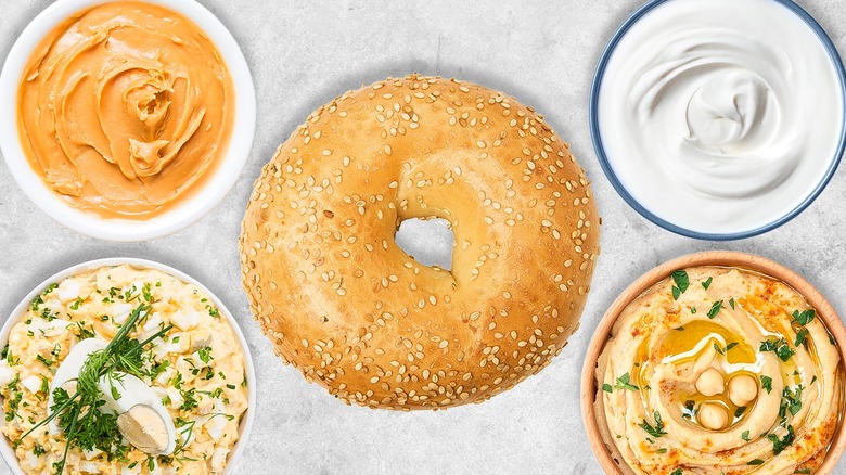 Bagel surrounded by different ingredients in bowls