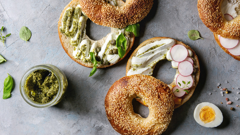 Bagels with pesto and radishes on surface