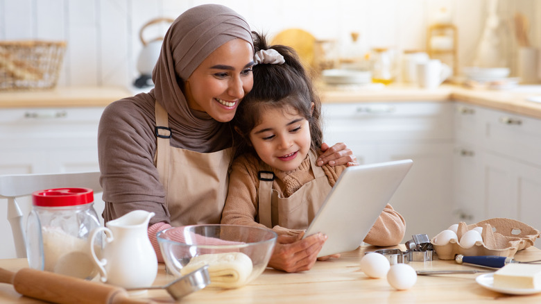 Mother and child reading recipe before baking in kitchen