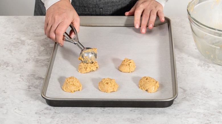 Person measuring out cookie dough with ice cream scoop