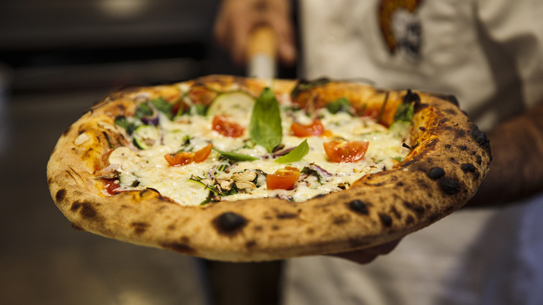 person holding freshly cooked pizza