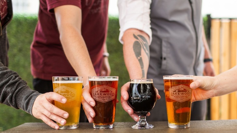 Hands holding beers in Lakewood Brewing Company glasses