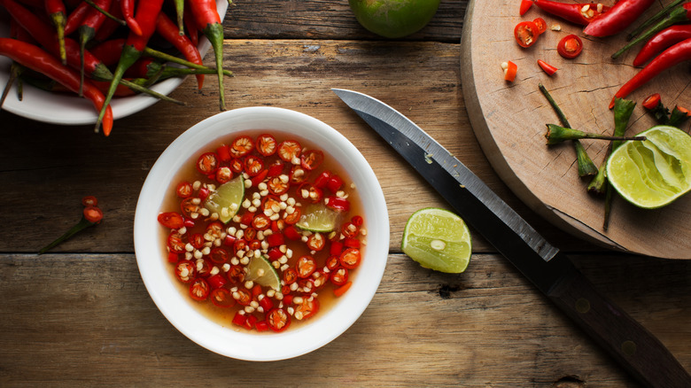 A bowl of fish sauce with sliced chiles and lime