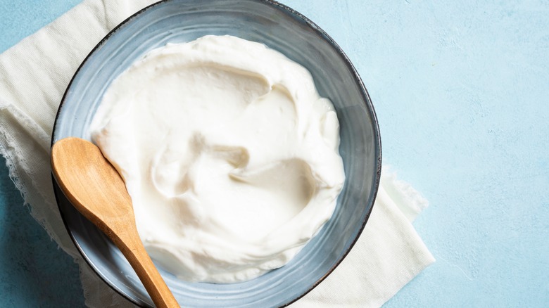 A blue bowl of Greek yogurt with a wooden spoon